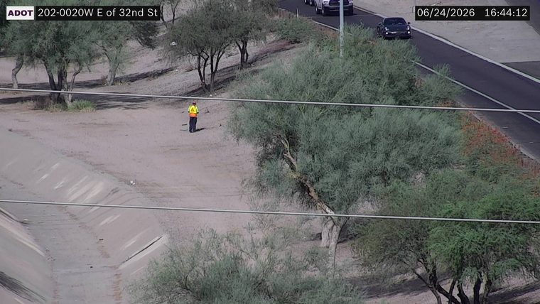 Person in high-visibility vest and orange vest on the dirt shoulder