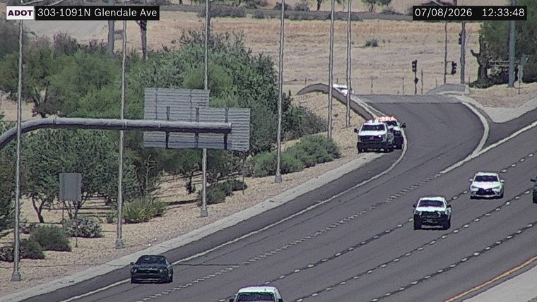 Two police vehicles with red and blue lights on the shoulder