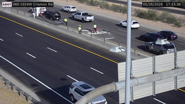 Tow truck loading a damaged SUV and workers cleaning a spill on the left shoulder, with a sheriff vehicle parked on the right shoulder