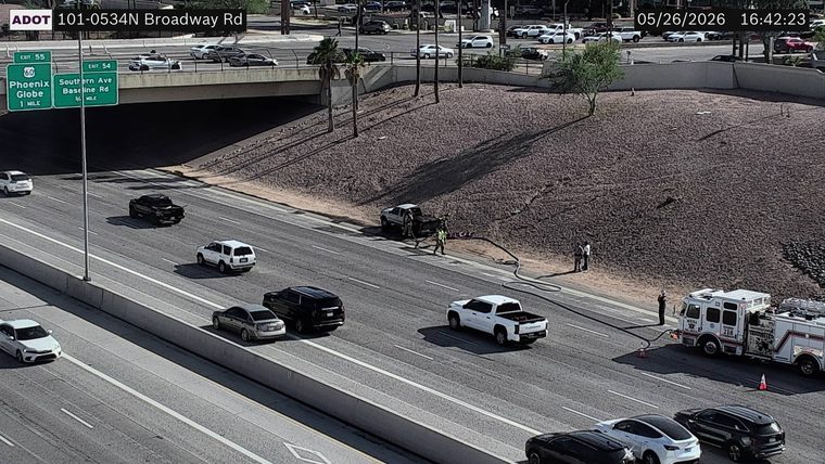 Fire engine on the right shoulder with responders and a hose deployed to a pickup truck on the embankment