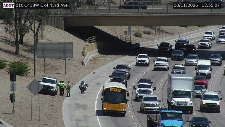 Two persons and a motorcycle officer near a white SUV on the right shoulder