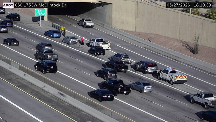 Multi-vehicle crash in the left-center lanes with responders, a rear-end damaged SUV, and a person standing next to a vehicle with an open door