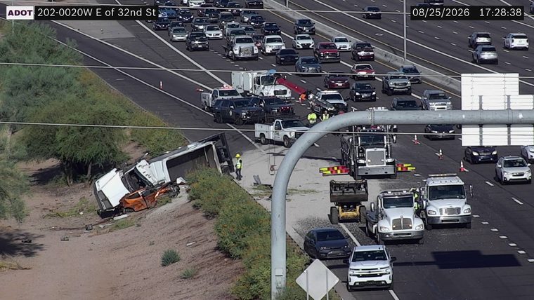 Tractor-trailer overturned on the left shoulder with debris in the lanes