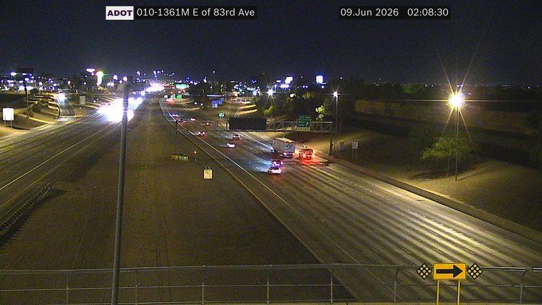 Two police cars and a fire truck with lights on in the right lane