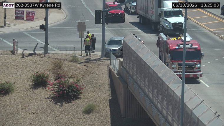 Silver SUV with visible front-end damage and two individuals in safety vests standing nearby