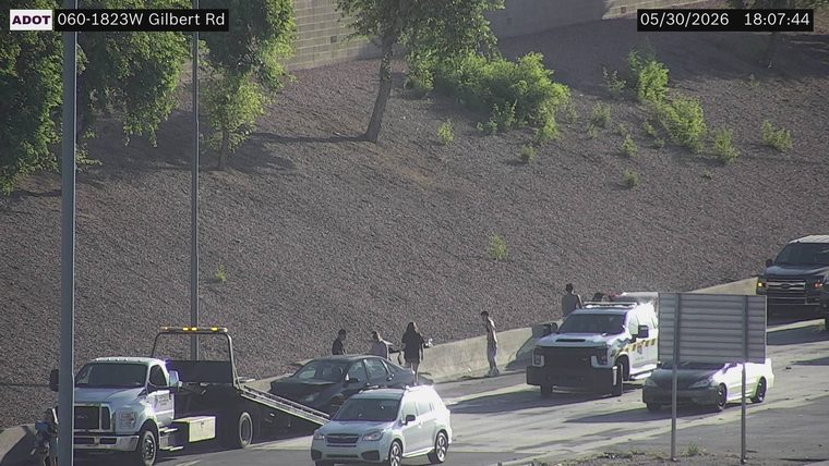 Tow truck and police vehicle with people around a car on the right shoulder
