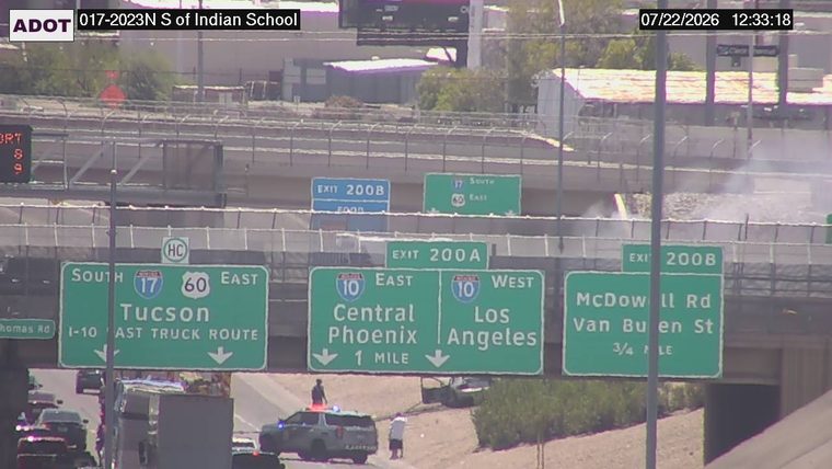 Police car with lights on the shoulder and two people standing near it