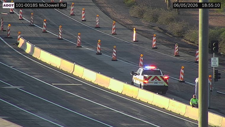 Service patrol vehicle with lights on and a person sitting on the barrier