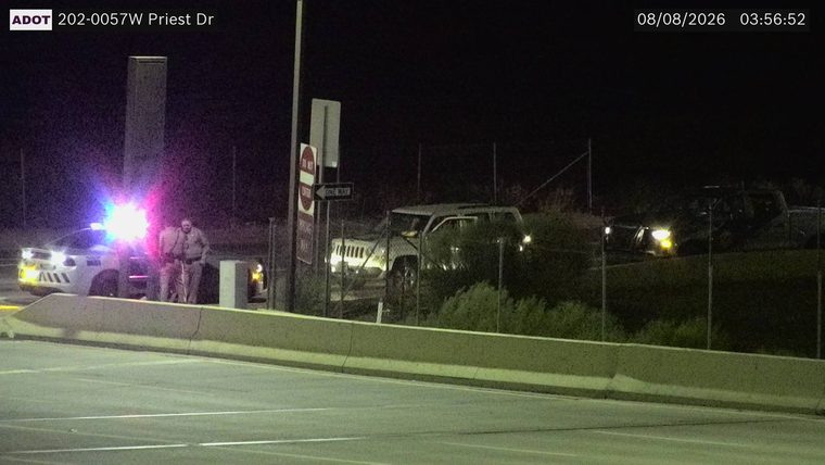 Police car with red and blue lights on, two officers standing nearby