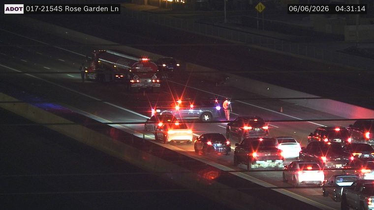 Person standing next to a car with hazard lights on in the left lane