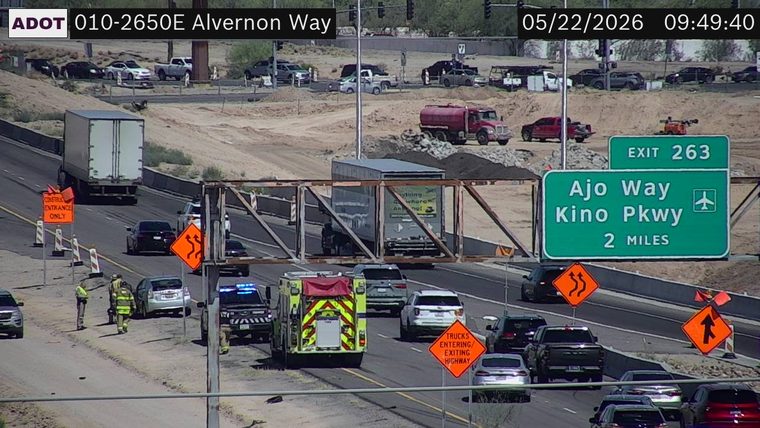 Emergency responders, including a fire truck and police car with flashing lights, on the left shoulder next to a silver SUV