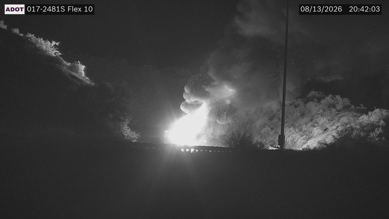 Large plume of smoke and flames visible above the roadway