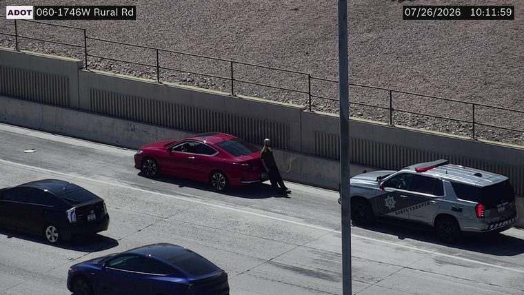 State Trooper vehicle with red and blue lights on the right shoulder next to a red sedan