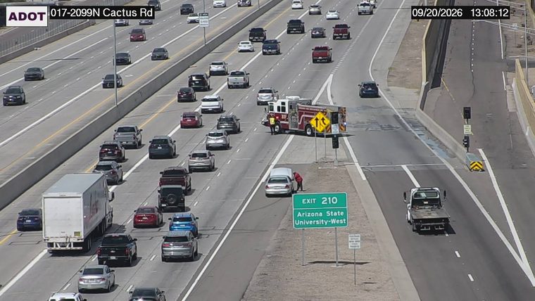 Fire truck with lights on the shoulder next to a car with its hood up