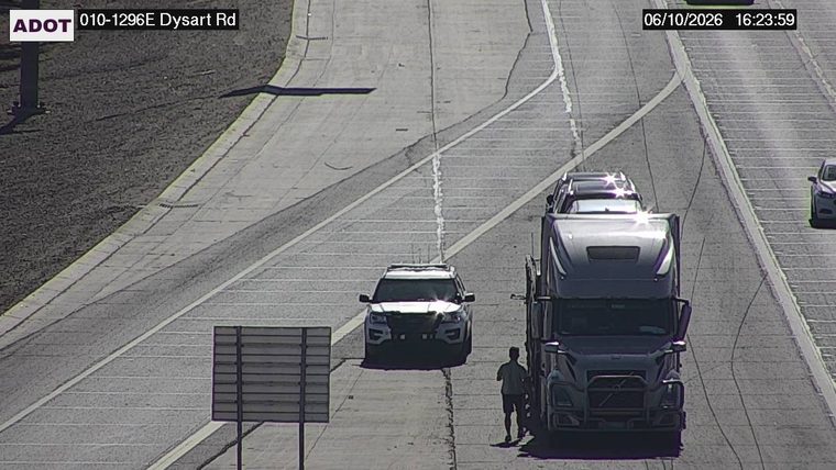 Person standing on the right shoulder next to a semi-truck