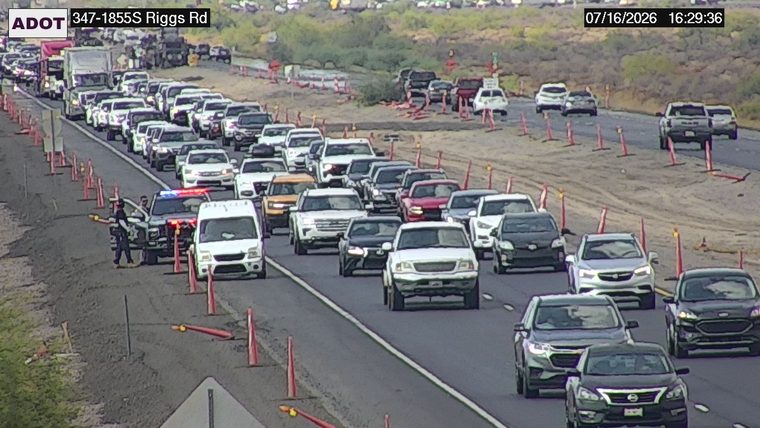 Police car with lights on in the left lane, directing traffic around construction