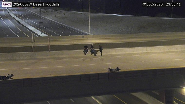 Three persons sitting on the highway barrier and two persons lying on the roadway