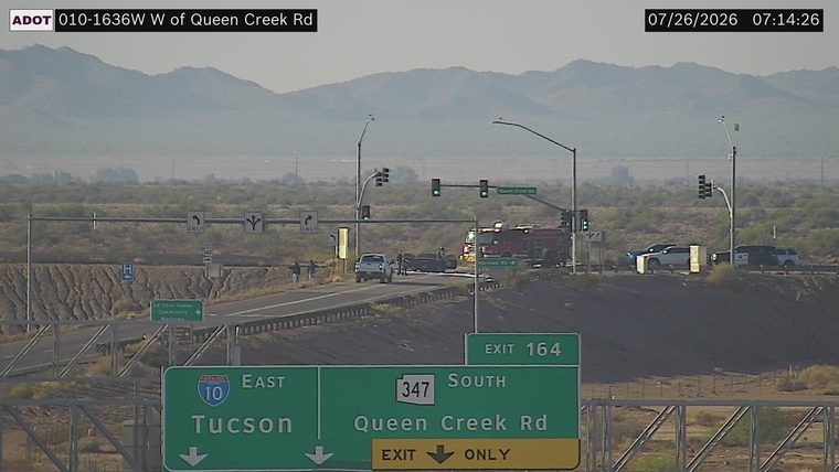 Fire truck and police car with emergency lights on near a damaged vehicle in the left lane