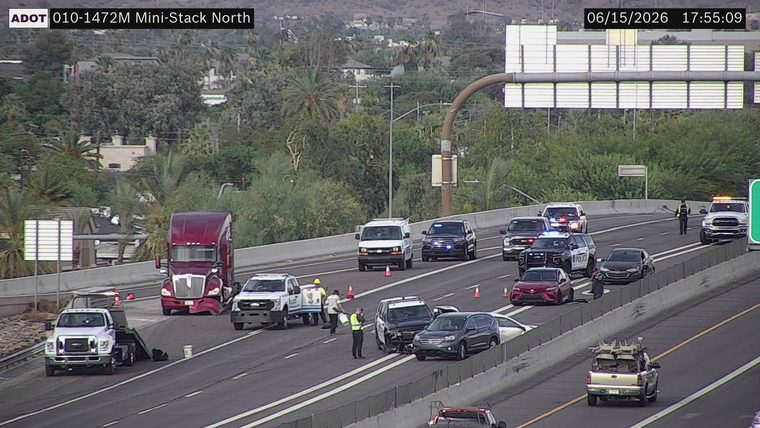 Multiple police vehicles and workers attending to a crash scene in the left lanes