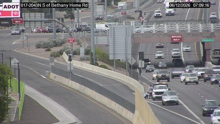 Two people attending to a white vehicle on the right shoulder