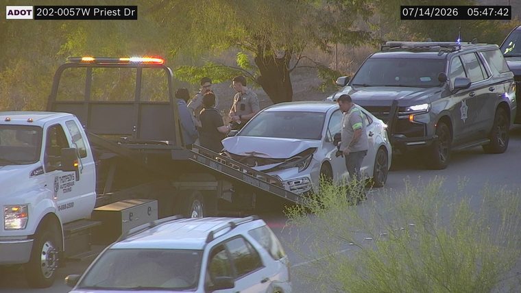 Damaged car being loaded onto a tow truck with law enforcement present