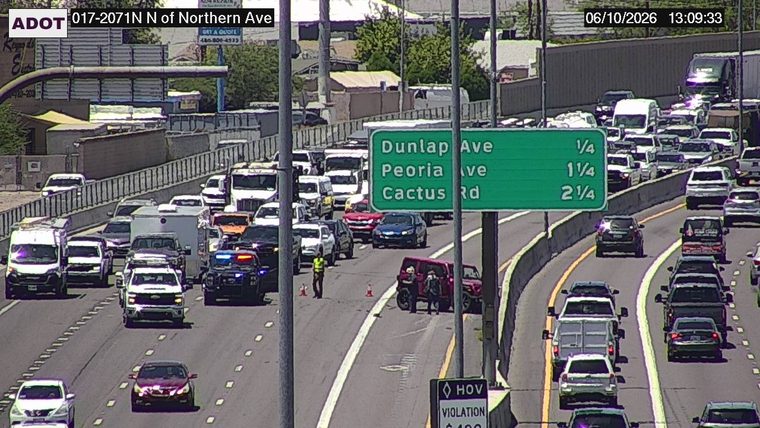Two individuals and a police car near a red SUV in the right lane