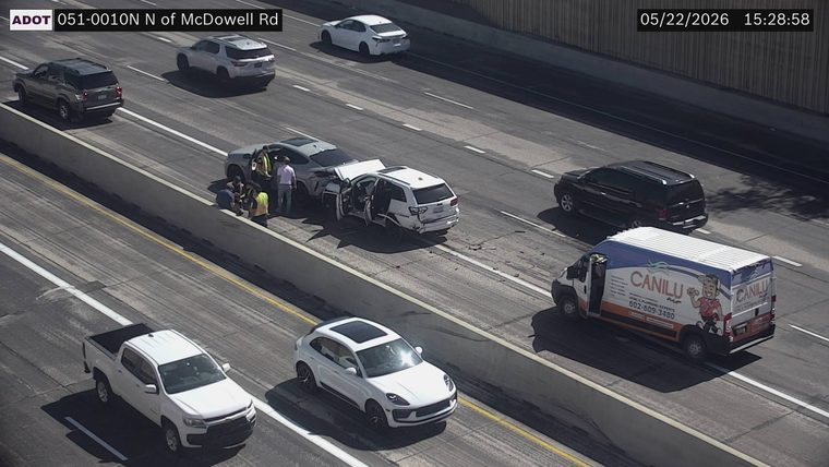 Two SUVs collided in the left lane next to the median barrier with people standing outside