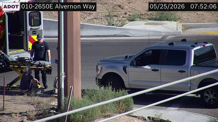 Ambulance with open doors and emergency responders with a stretcher on the left side of the road