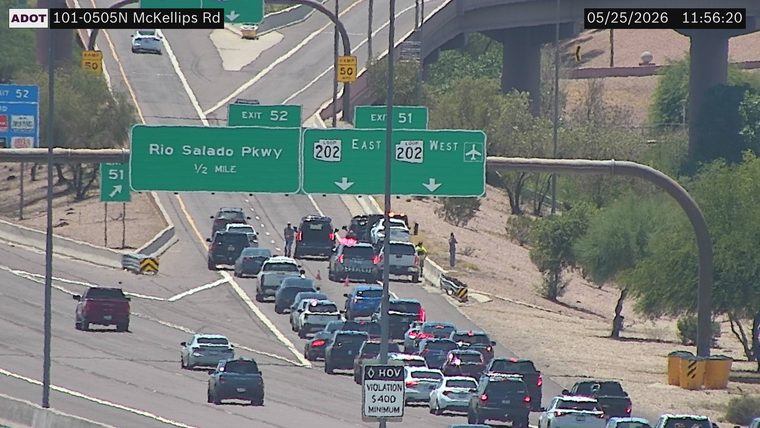 Multiple vehicles collided in the travel lanes with people standing outside and a responder vehicle with flashing lights