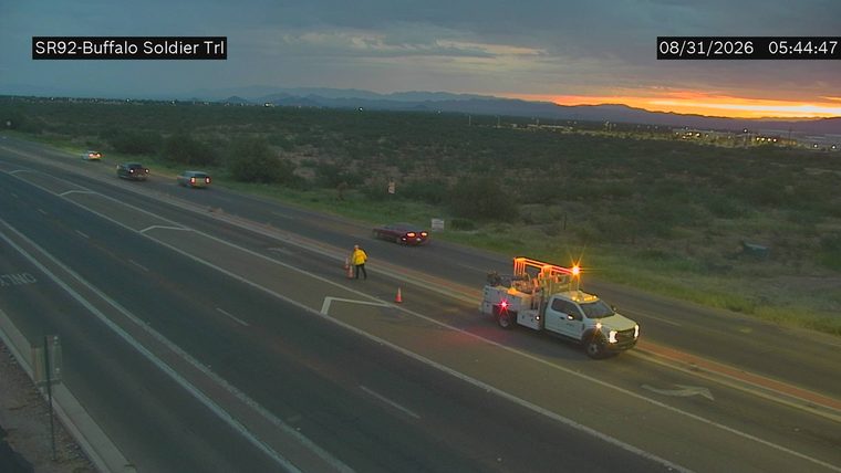 Worker and cones in the right lane next to a service truck with flashing amber lights