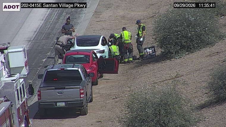 Fire truck and emergency personnel attending to a white vehicle on the shoulder