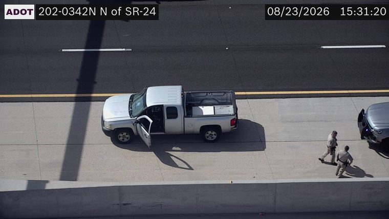 Two persons in uniform near a silver pickup truck with its doors open