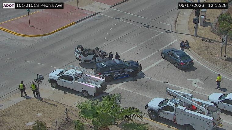 Overturned white SUV with a police car and two officers present in the intersection