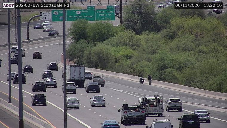 Person standing next to a motorcycle on the right shoulder