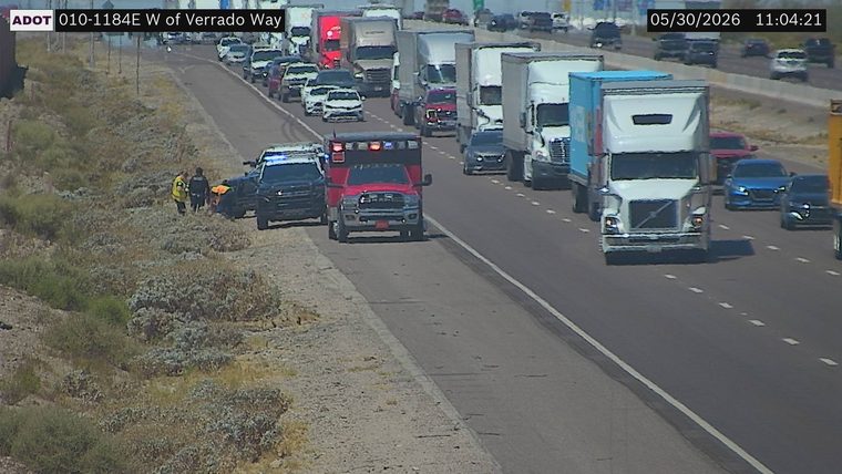 Police car and ambulance on the right shoulder with two people standing nearby