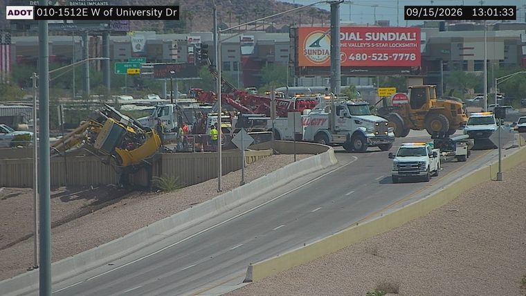 Excavator off the roadway and tilted over the barrier