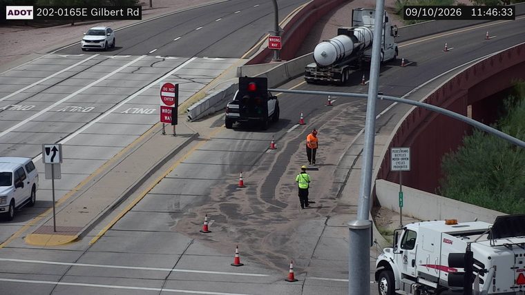 Two workers in high-visibility vests and a truck with a traffic signal in the roadway