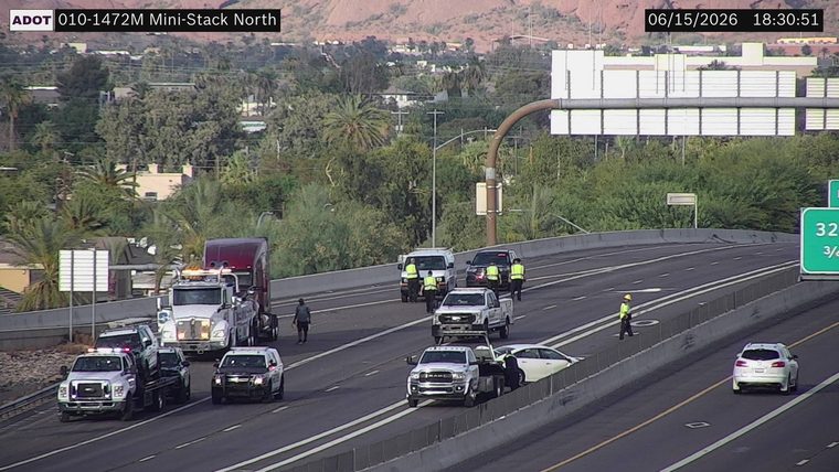 Tow truck and multiple vehicles with people in high-visibility vests on the roadway