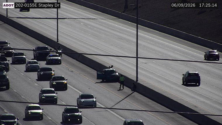 Person in high-visibility vest near a car with open door on the right shoulder
