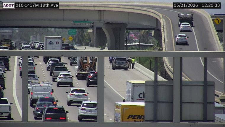 A dark SUV stopped on the right shoulder with a responder in a high-visibility vest and another person standing outside.