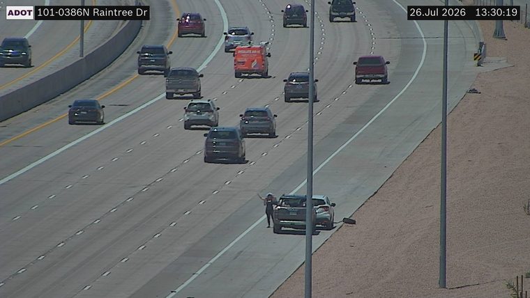 Person standing next to a vehicle on the right shoulder