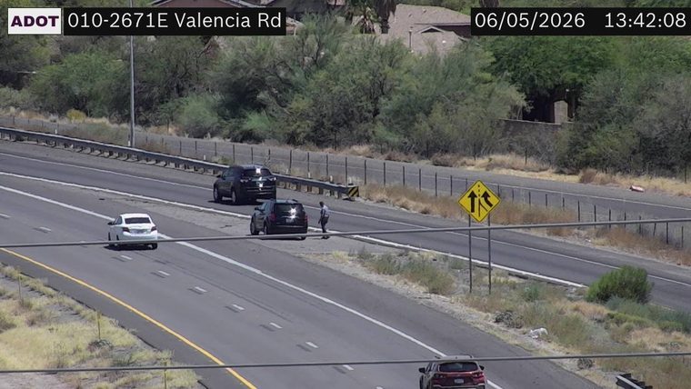 Person standing in the right lane next to a dark SUV