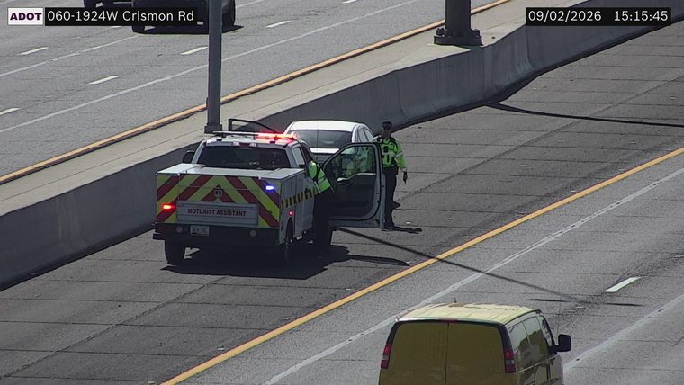 Motorist assistance truck with red and blue lights on the right shoulder, assisting a white vehicle