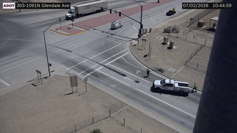Two workers in high-visibility vests near a white truck in the roadway