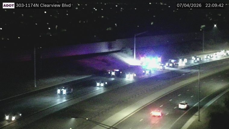 Multiple emergency vehicles with flashing red and blue lights in the left lanes