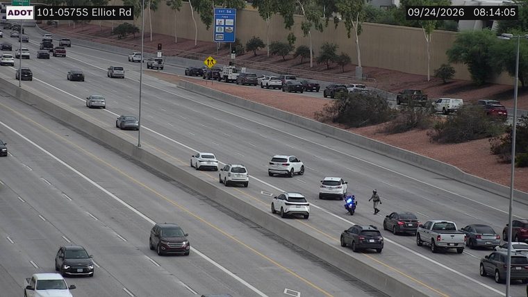 Person walking in the roadway near a motorcycle with blue lights on