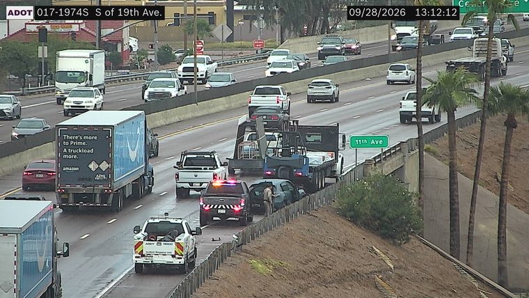 Police car with red and blue lights on the right shoulder next to a damaged vehicle