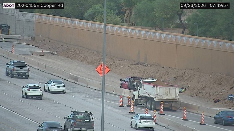 Construction cones and a worker near a dump truck in the right lane