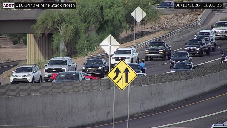 Person standing on the roadway next to a black car
