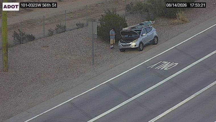 Silver SUV pulled over on the right shoulder with the hood up and a person standing next to it.